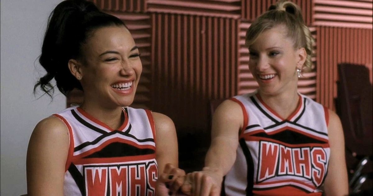 Naya里维拉作为“Santana"和希瑟·莫里斯“Brittany"笑在一起他们啦啦队制服