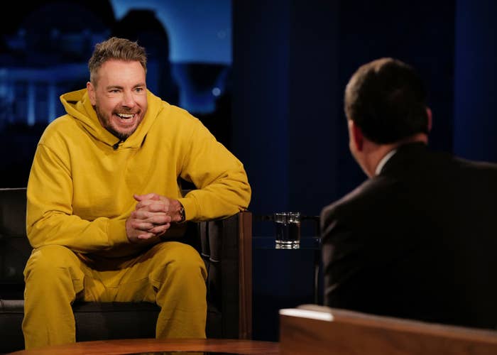 Dax in a yellow sweater set on a late night talk show