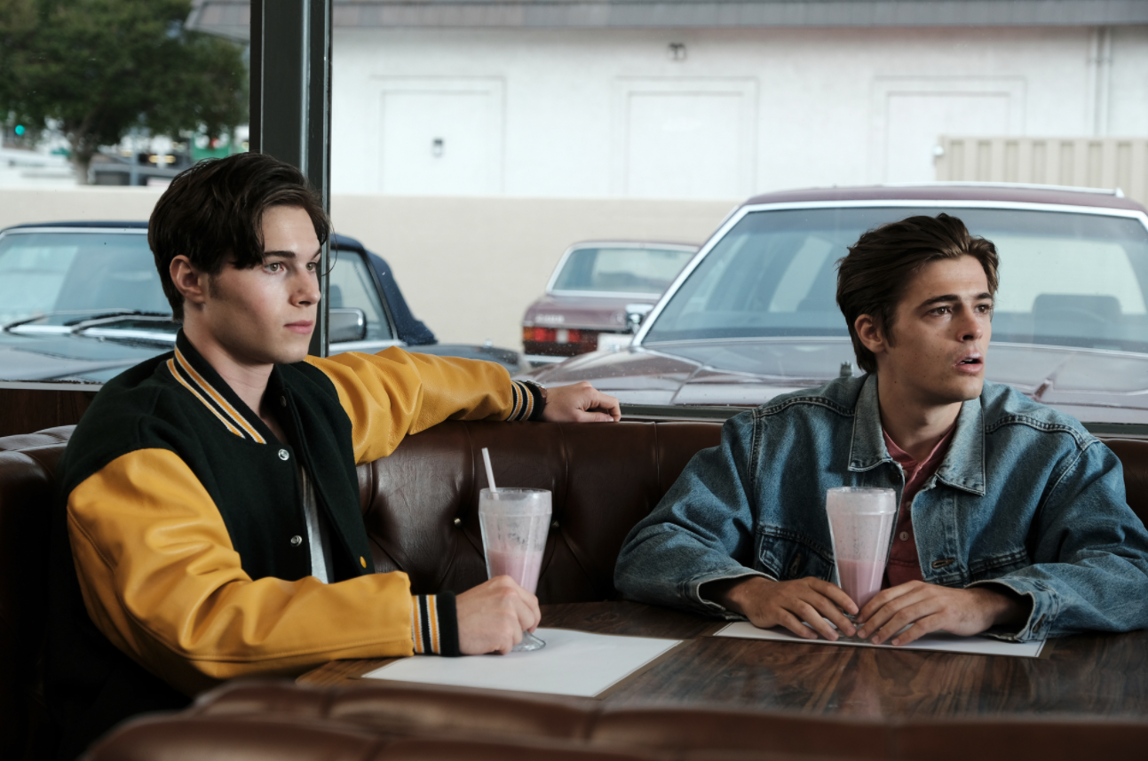 Young Cal and Derek sitting at a table drinking milkshakes