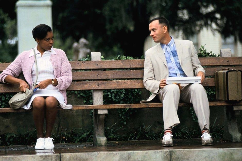 Tom Hanks as Forrest Gump sitting on a bench speaking to Rebecca Williams as the nurse