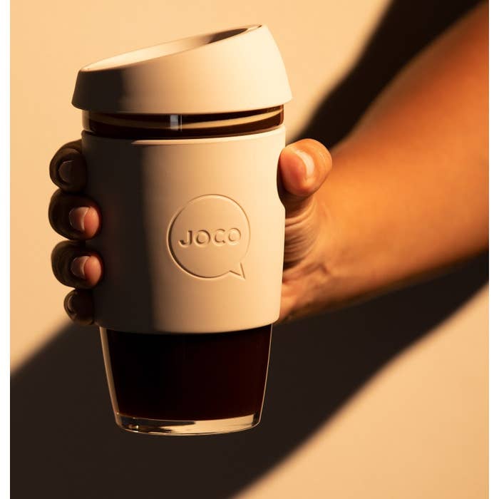 A person holding a large glass coffee cup