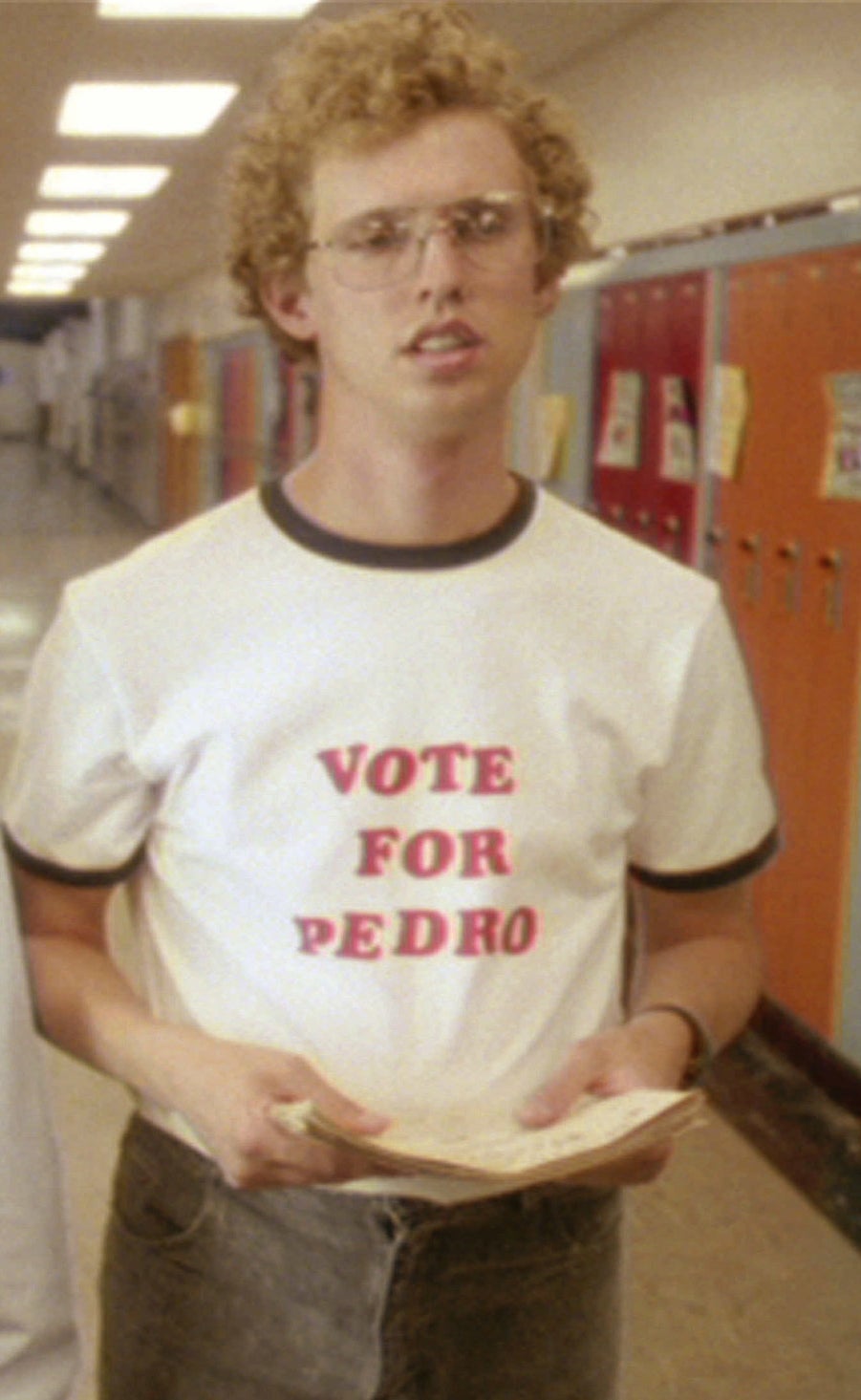 Napoleon Dynamite walks down the hall wearing his Vote for Pedro shirt