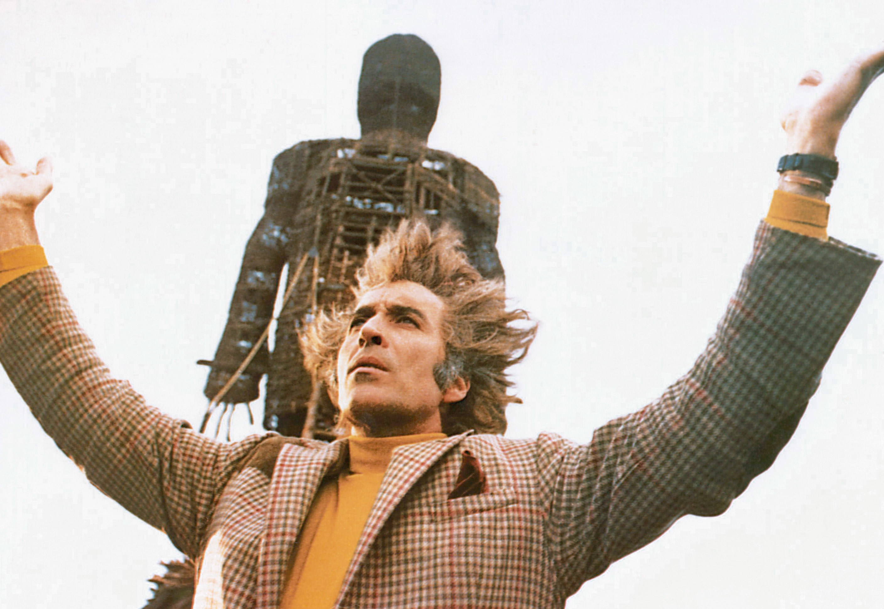 standing in front of the wicker effigy, Summerisle lifts his hands in praise