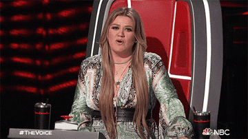 kelly clarkson holding out hands and saying &quot;what?!&quot; on nbc&#x27;s the voice
