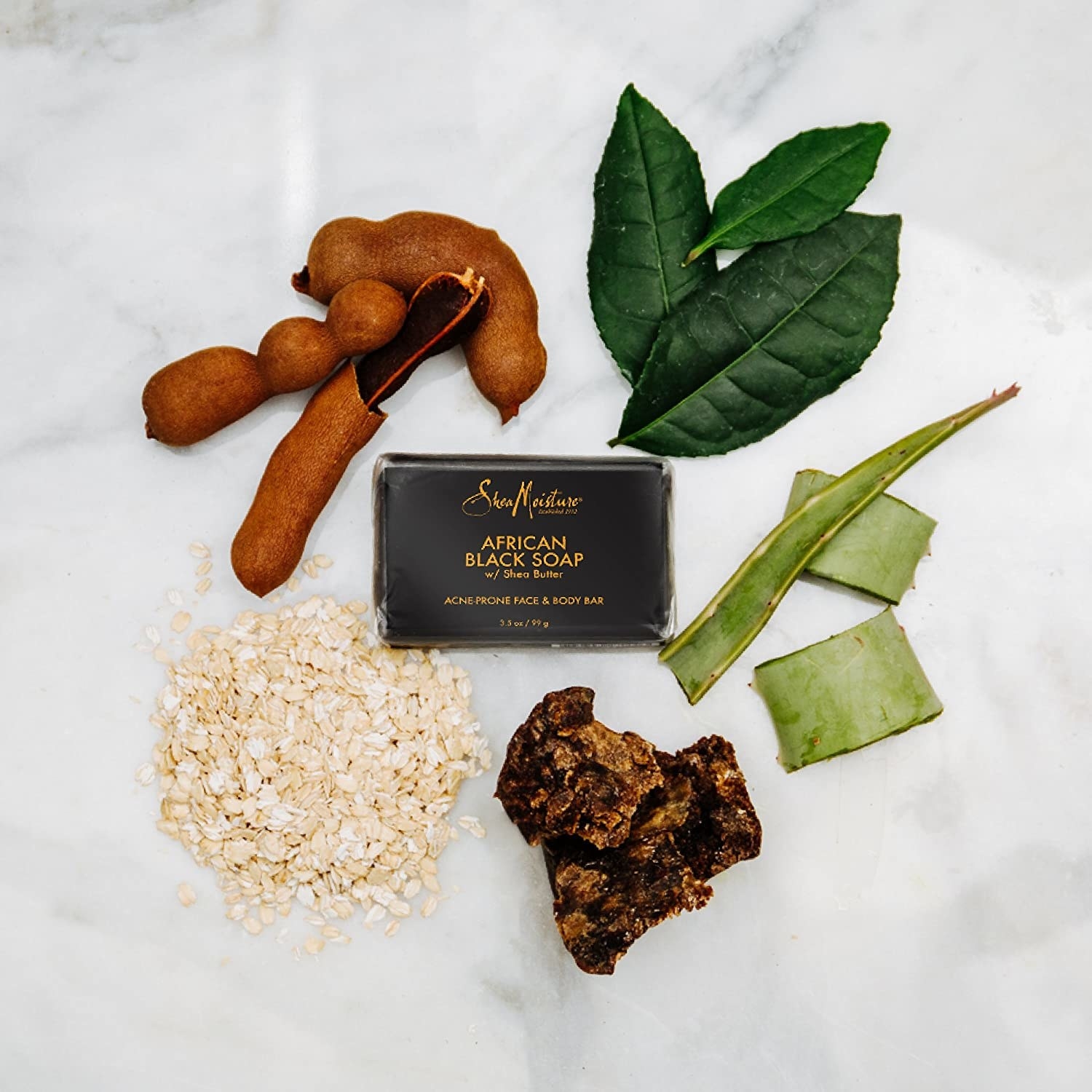 the bar of black soap surrounded by some ingredients