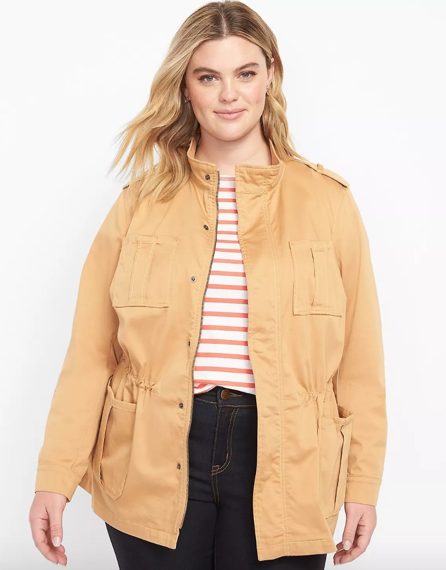 Model wearing beige jacket over striped shirt and dark jeans