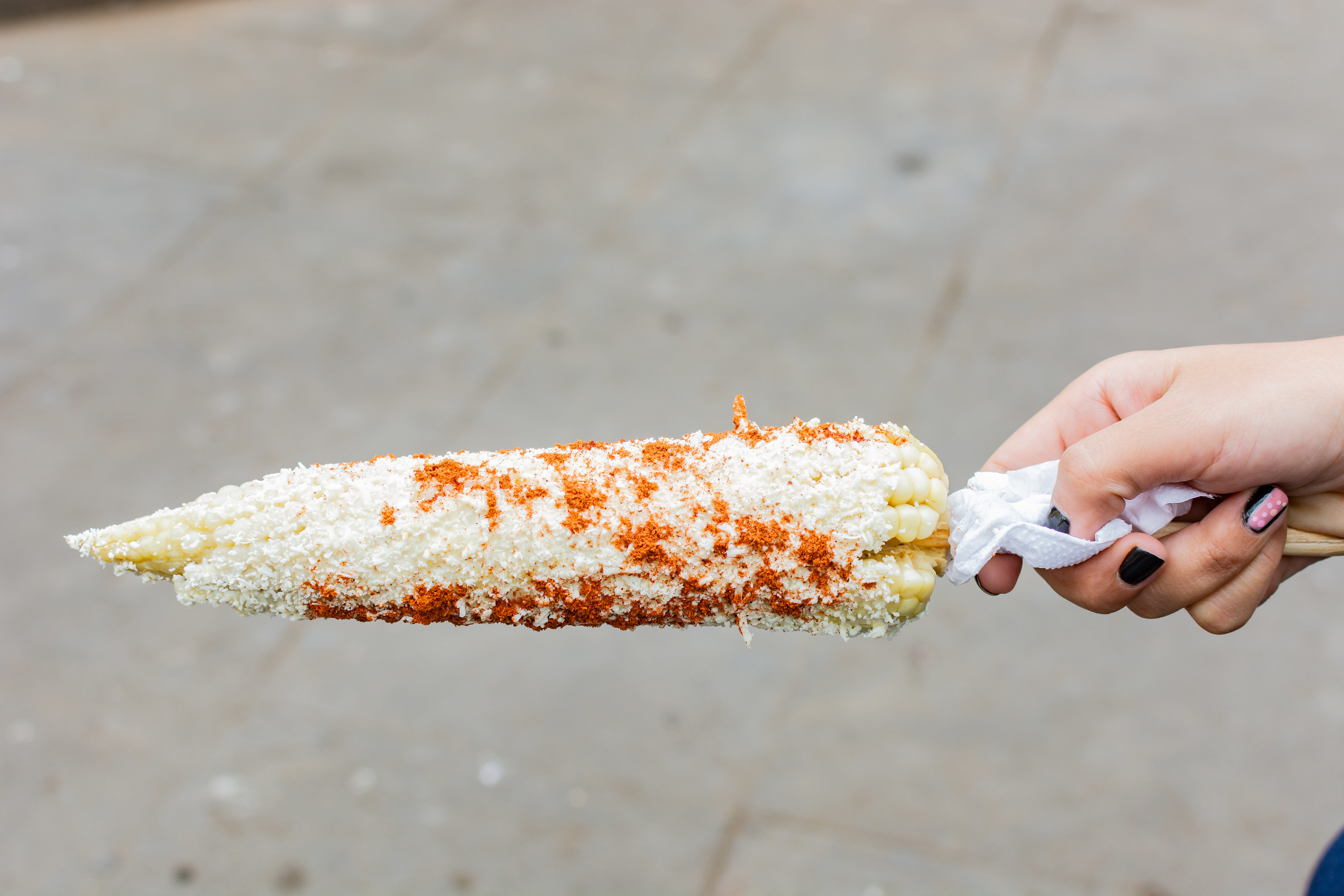 Someone holding an elote preparado in the street