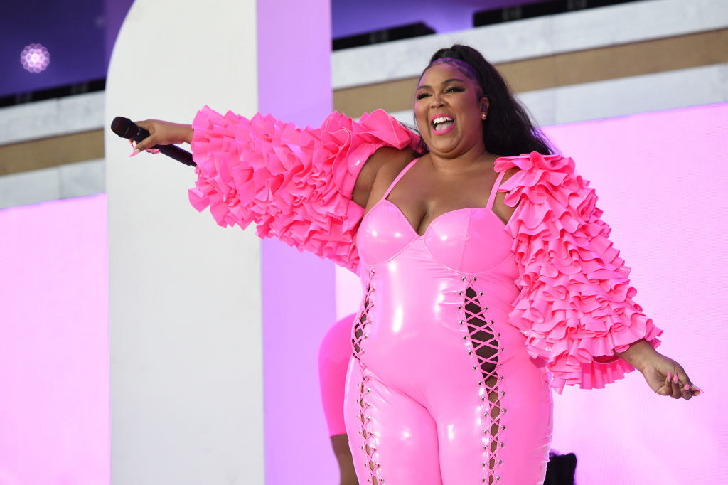 Lizzo in a bodysuit with laces up the side as she smiles onstage