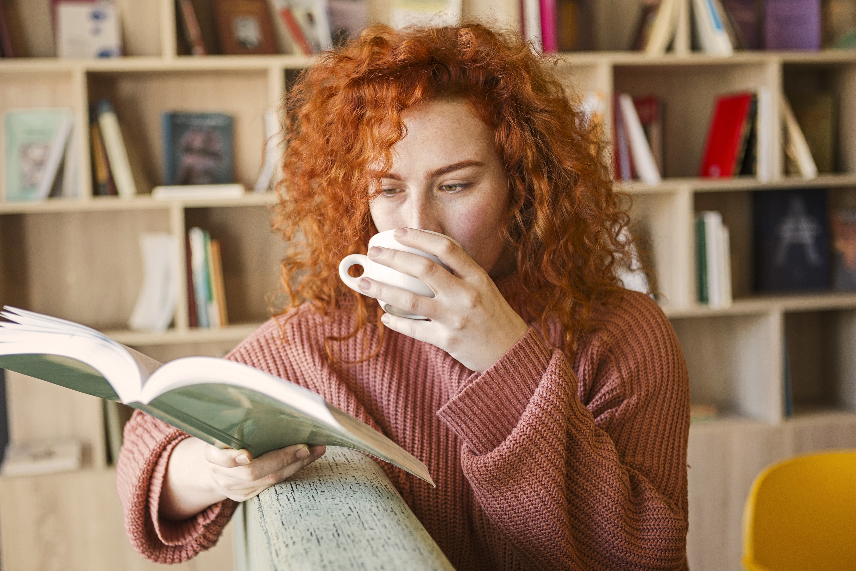 Woman reading a book while drinking her morning coffee