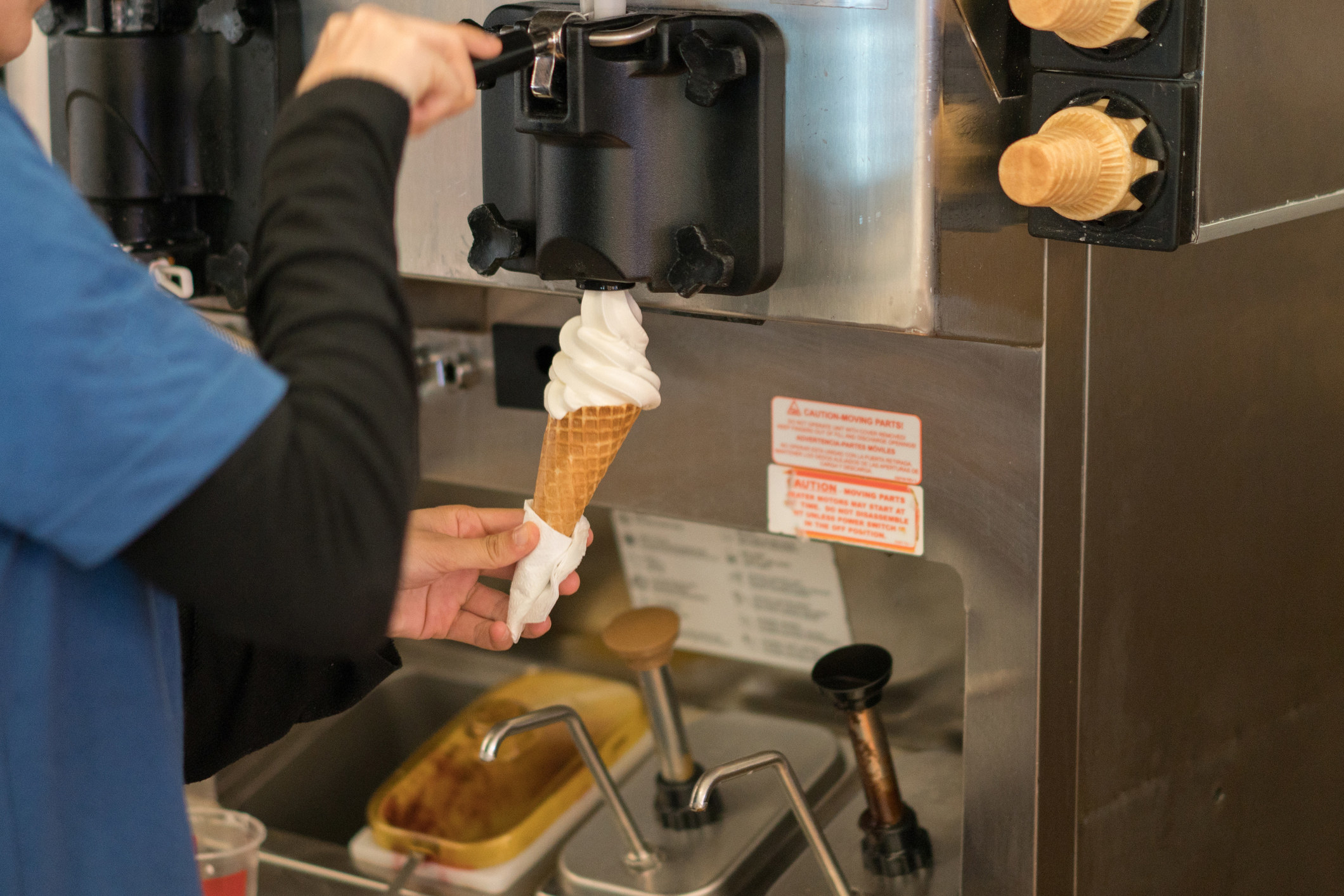 Someone filling a cone at an ice cream machine
