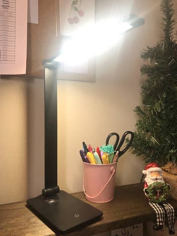 a reviewer black lamp turned on and sitting on a desk