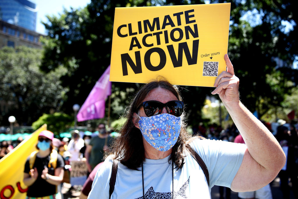 person holding sign at a rally that says &quot;climate action now&quot;