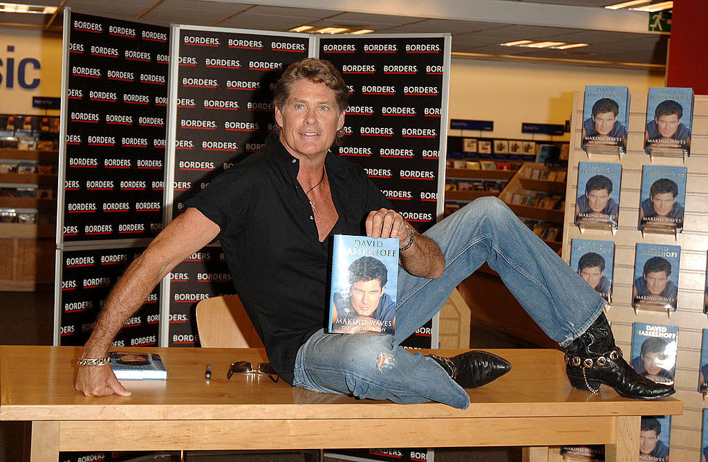 David posing on a table while holding his book