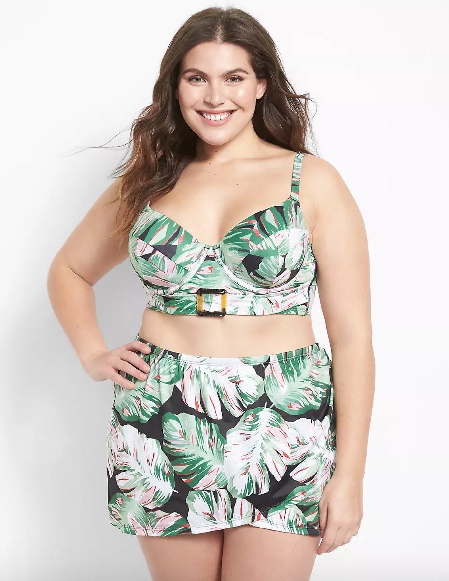 Model wearing leaf patterned green, white and black bikini with matching swim skirt