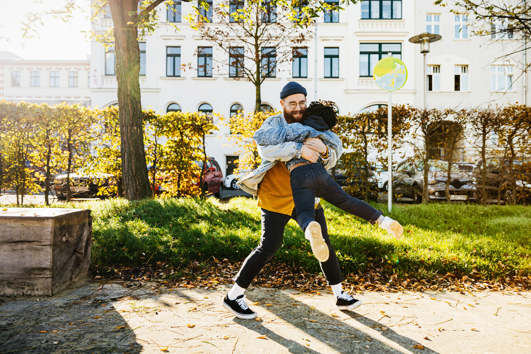 A father swings his child around in his arms in the park.