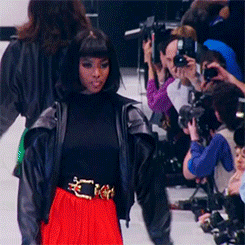 Naomi Campbell walks the runway in a red skirt and black leather jacket