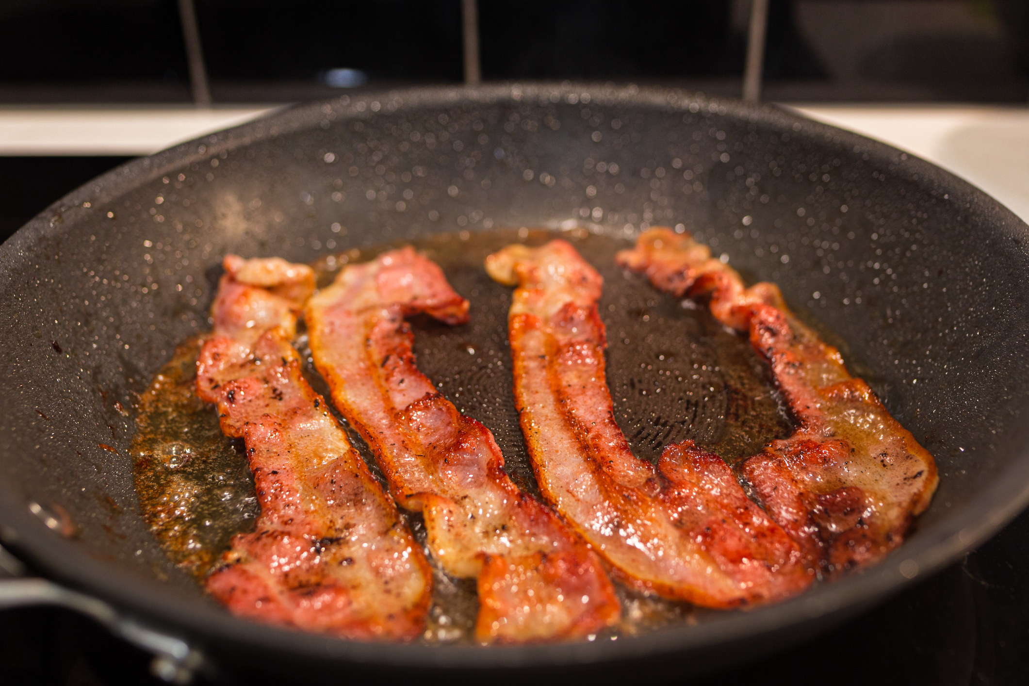 Bacon being fried in a skillet