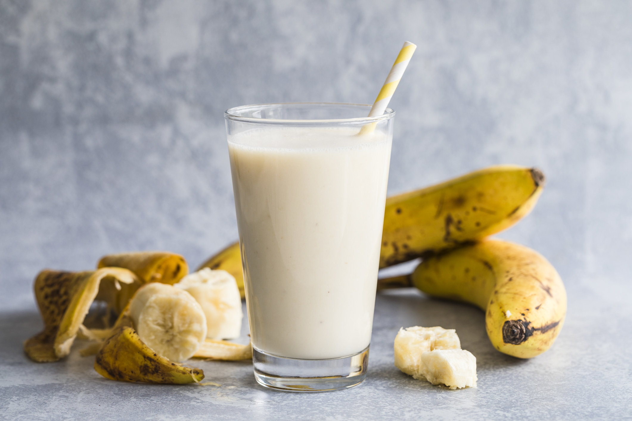 A banana smoothie and bananas in the background.