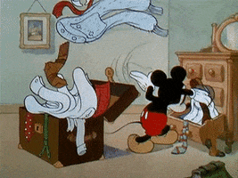Gif of Micky Mouse throwing clothes behind him into a suitcase