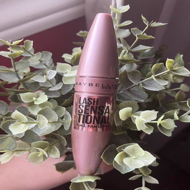 A tube of mascara resting in a plant