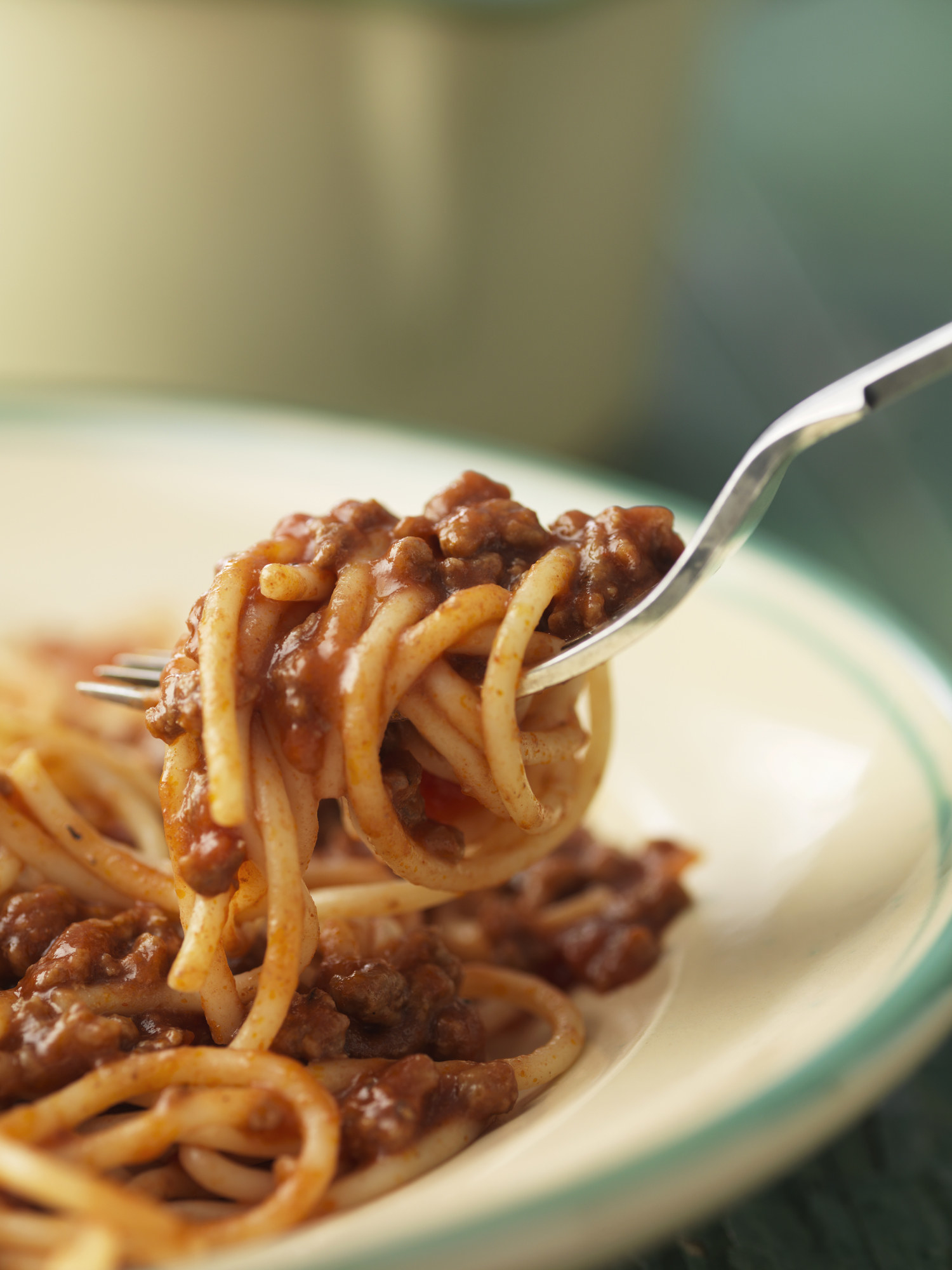 Spaghetti and meat sauce on a fork over a plate