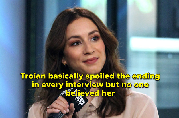 Troian Bellisario sits in a chair holding a microphone, wearing a pale pink shirt