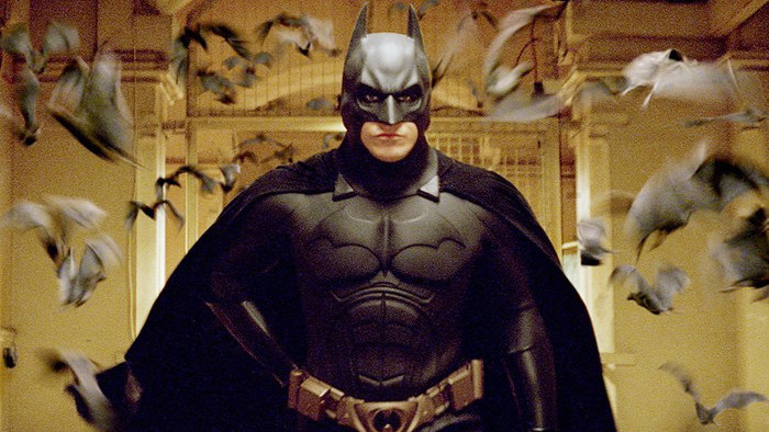 Christian Bale as Batman walks down a hall filled with bats