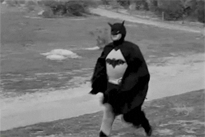 Robert Lowery as a black and white Batman jumps into frame and looks around
