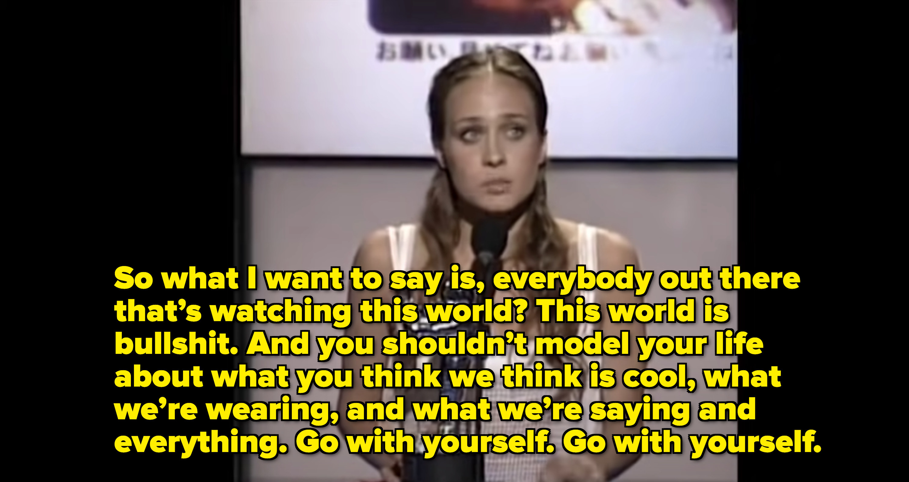 Fiona standing at the podium with quote from her that "this world is bullshit" and "you shouldn't model your life about what you think we think is cool, what we're wearing, and what we're saying and everything"
