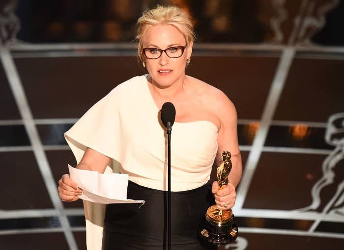 Patricia Arquette standing at the podium holding an award and a piece of paper