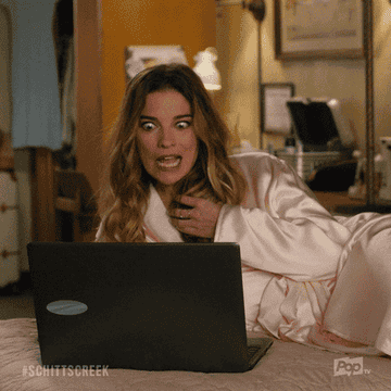 A woman in a bath robe laying down looking at her computer saying, &quot;yum!&quot;