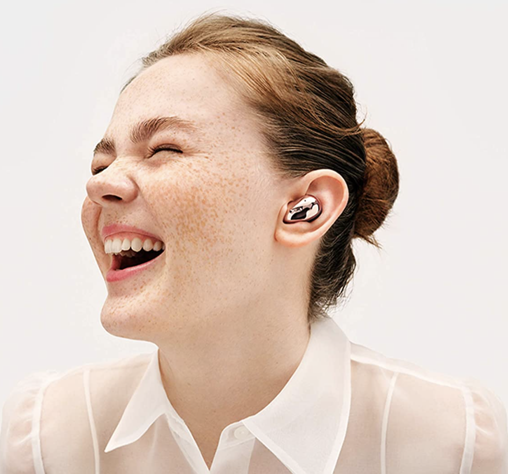 Model is laughing with rose gold earbuds in her ear