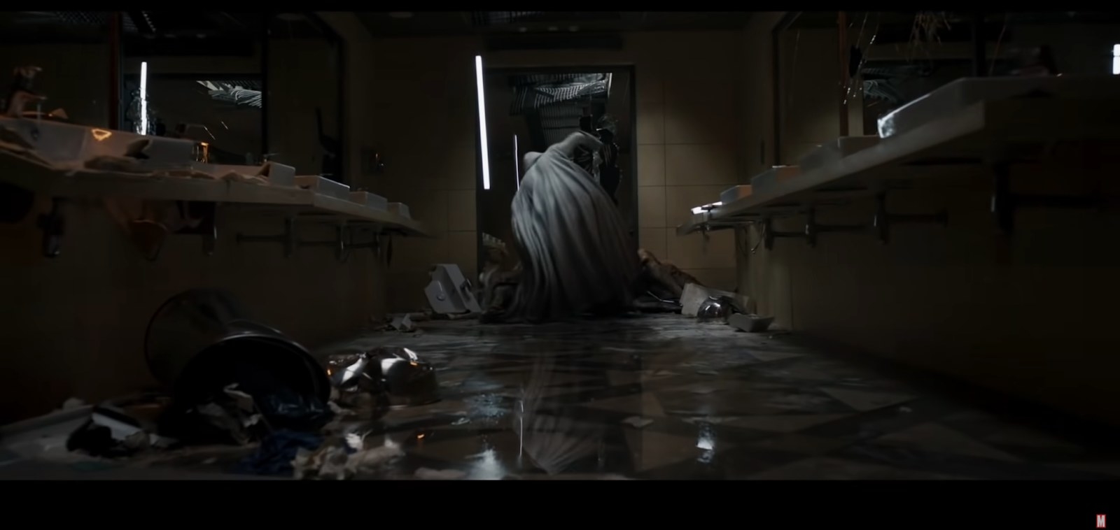 Moon Knight standing above a person lying on the floor, appearing to hit them
