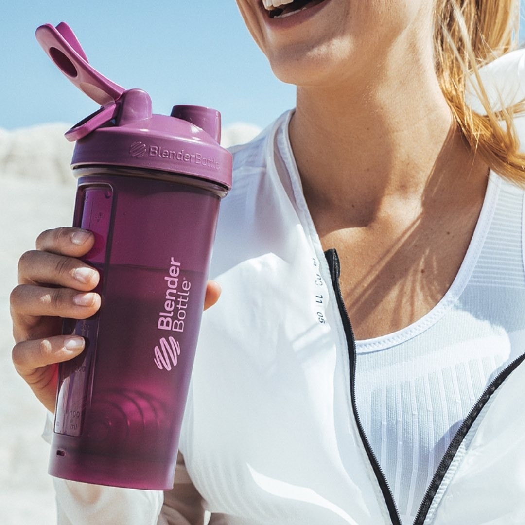 a smiling person sipping from the blender bottle