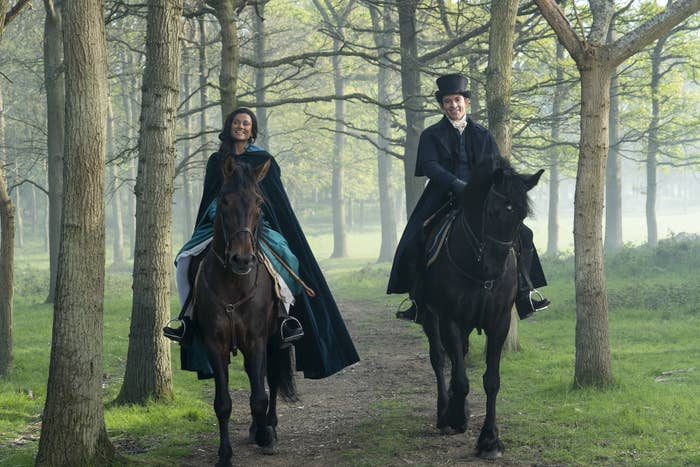 Two people riding horses in the woods