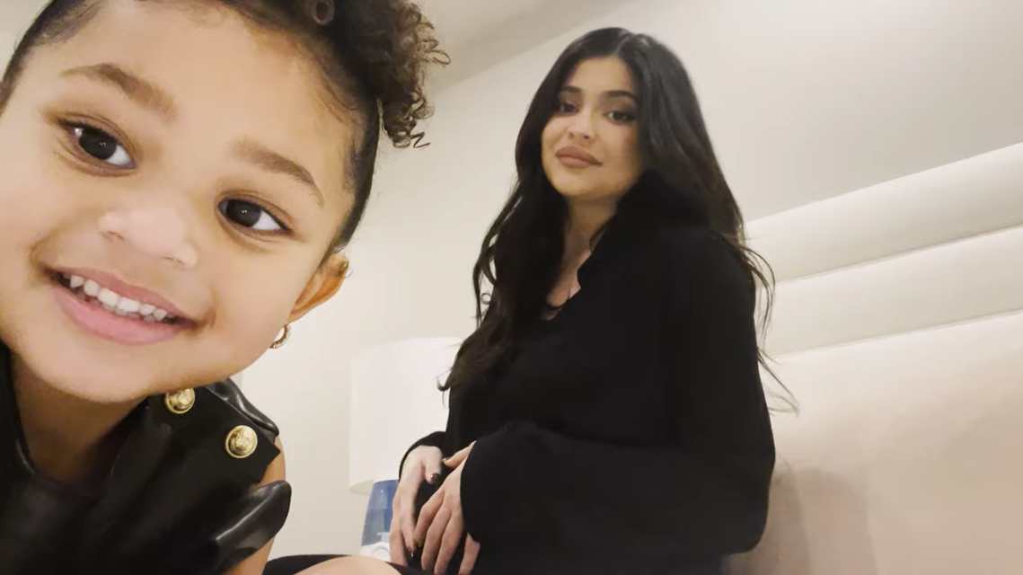 Stormi smiling in the foreground with Kylie holding her pregnant belly in background
