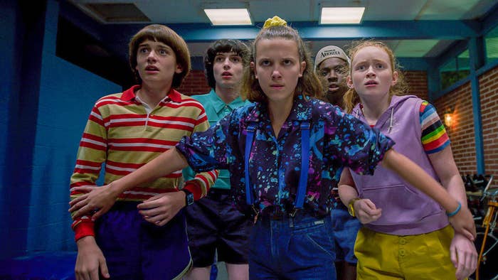 eleven, will, mike, max, and lucas in a hallway, all with big eyes, eyebrows up as if scared