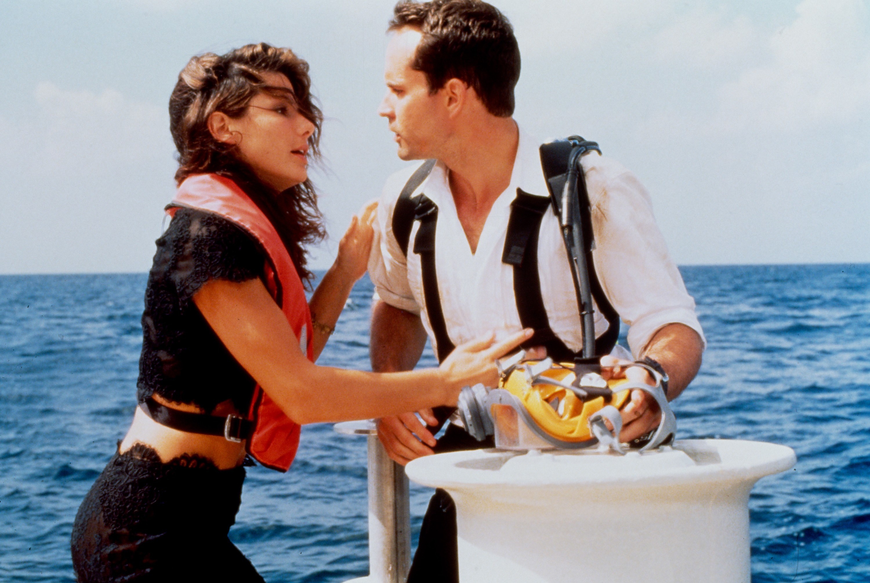 Sandra puts her hands on Jason Patric while wearing a life vest