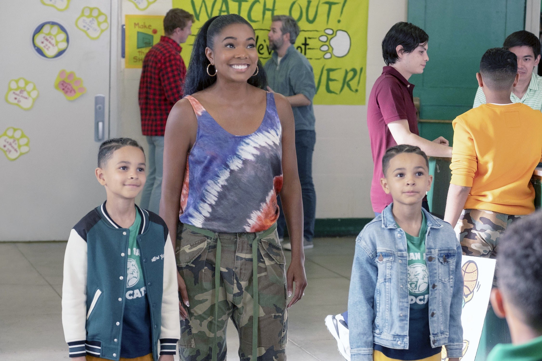 Gabrielle standing in a room flanked by two kids in a scene from the film