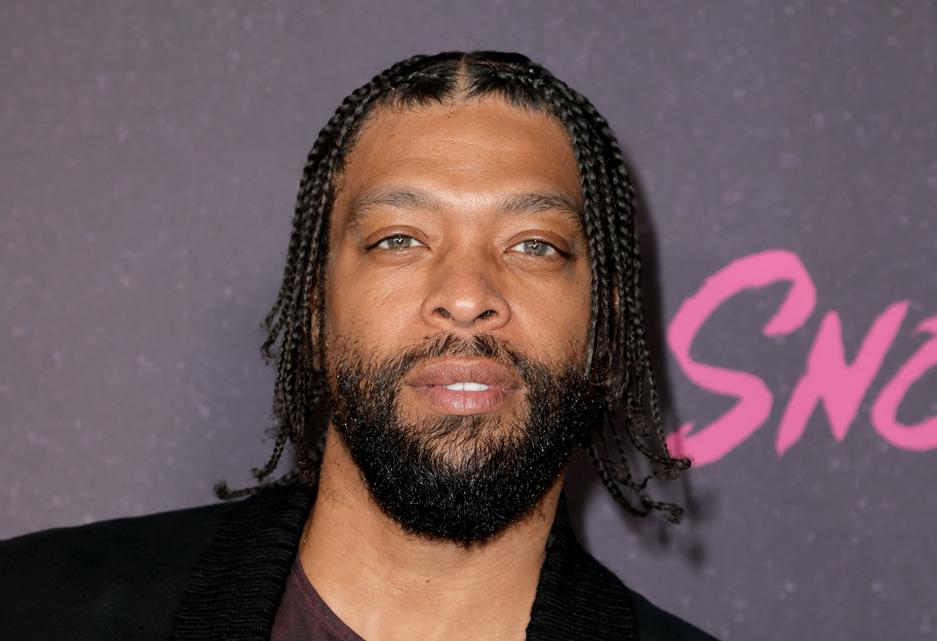 DeRay Davis poses with a straight face on the red carpet at a Snowfall premiere