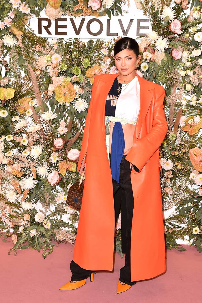 Kylie poses in front of a wall of flowers at an event