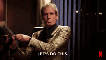 Michael Bolton in a gold suit and black shirt cocking a gun saying &quot;Let&#x27;s do this&quot; in his big sexy valentines day special
