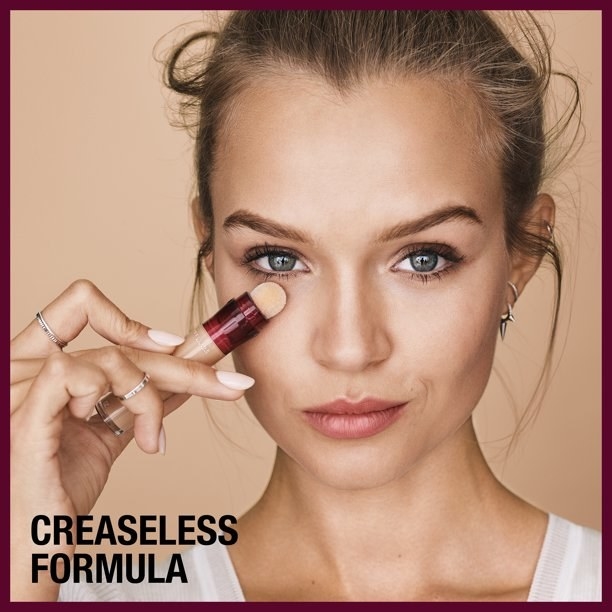 model applying the under-eye concealer with caption creaseless formula