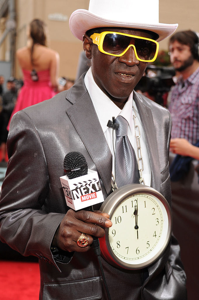 Flavor Flav with a large clock around his neck at a red carpet event