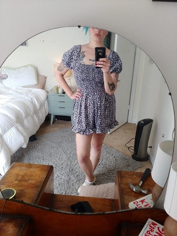 A reviewer wearing a ruffled short sleeve sleeve romper in blue