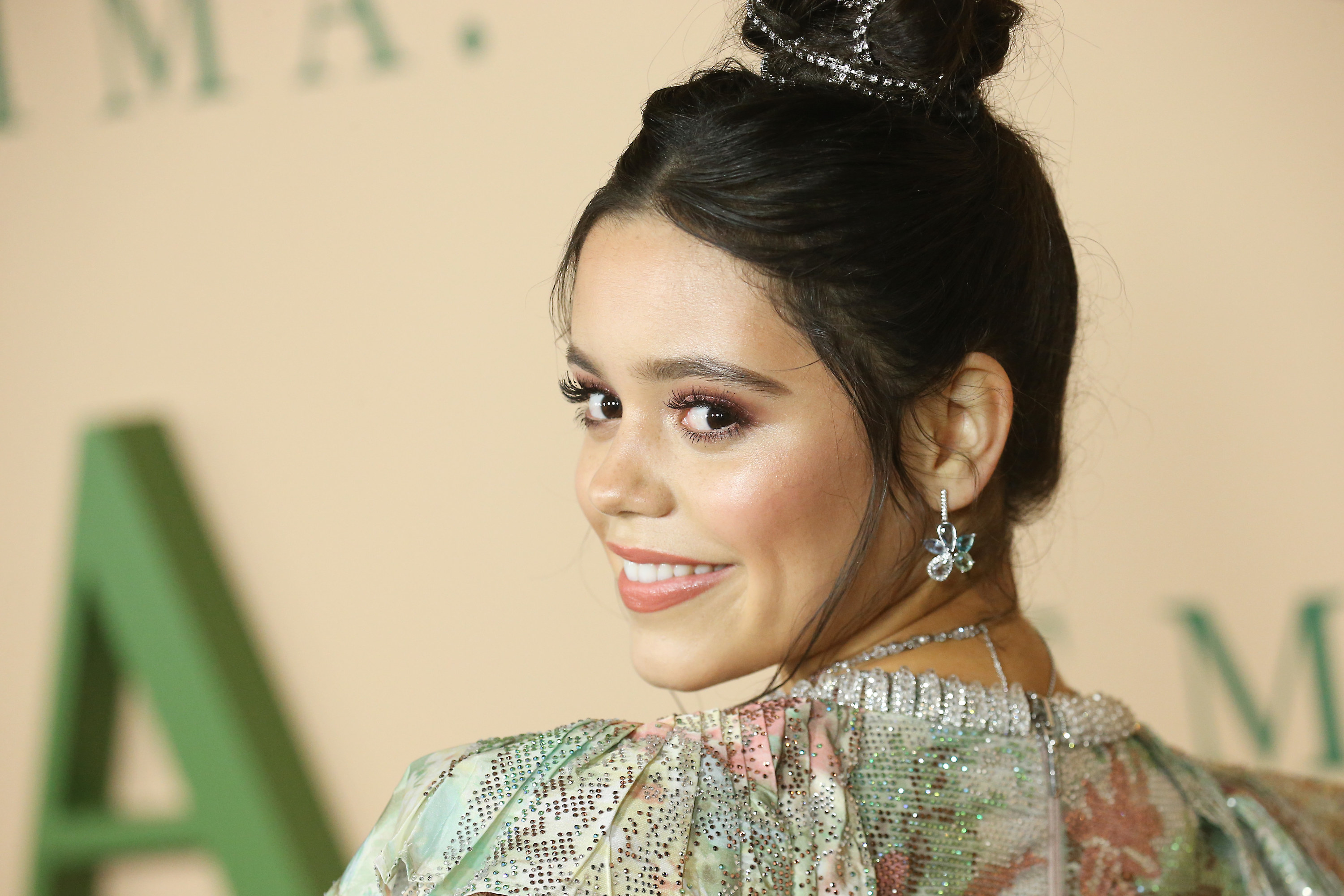 Jenna Ortega smiling and looking over her shoulder