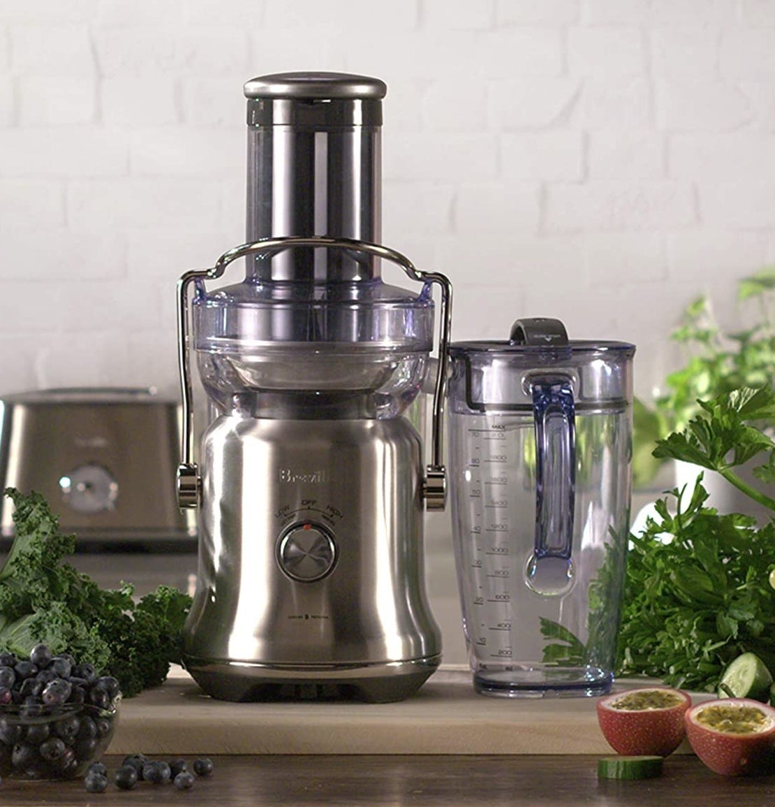 A juicer on a counter with fresh fruits and veggies