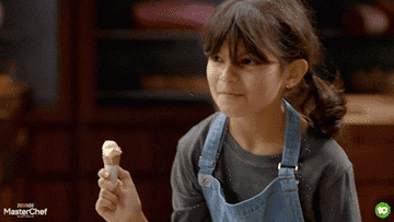 一个孩子从“低级Masterchef"做一个令人厌恶的脸,手里拿着一个小冰淇淋蛋卷