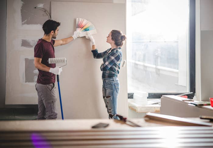 Contractor holding a paint roller discussing paint color with the homeowner