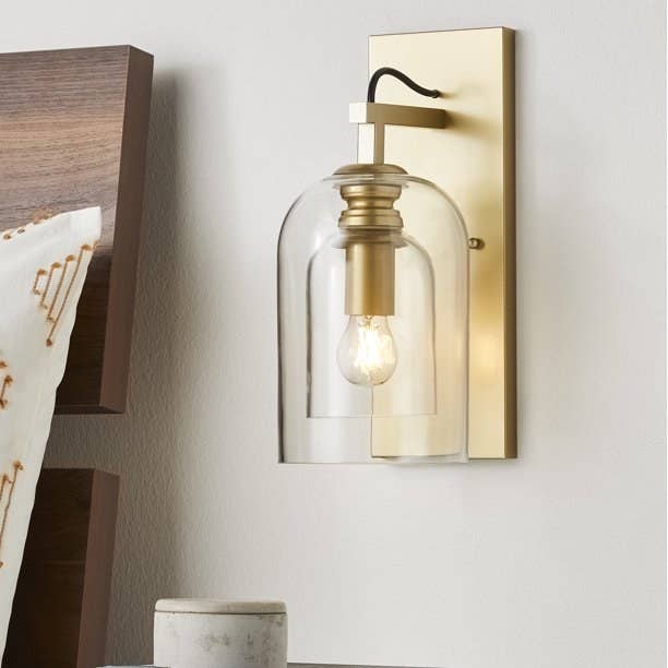 the brass sconce with double glass shades hanging on a wall